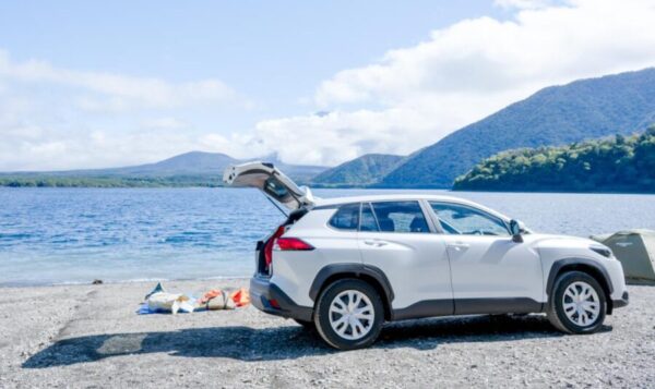 山と湖を背景に停車した青とシルバーのコンパクトSUV。荷室を開けてアウトドア用品を積み込む様子から、5人乗りSUVの積載性を紹介。