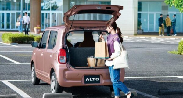 トヨタのピクシス エポックをイメージしたベージュの軽乗用車と、買い物袋を持つ日本人女性。通勤や買い物など日常使いに適したコンパクトな軽自動車のイメージ。